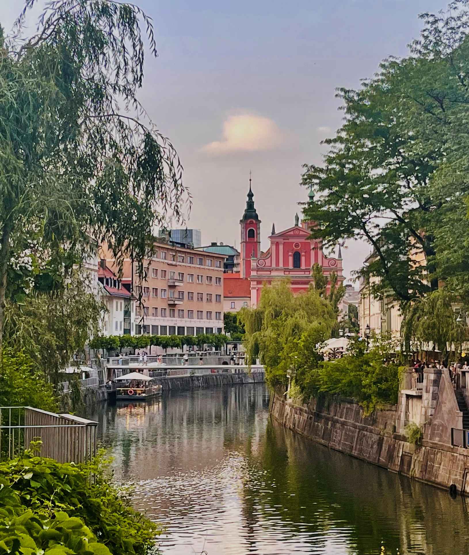 Bright salmon colored building dominates the other buildings along the river in Ljubljana Slovenia